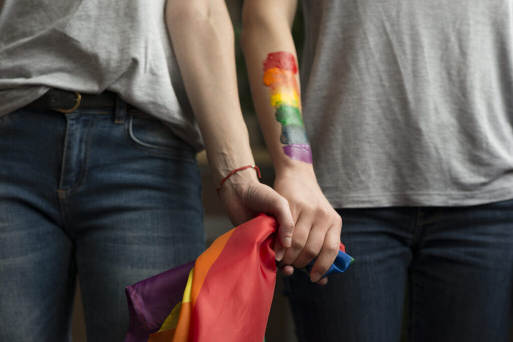 close-up-lesbian-couple-holding-lbgt-flag-hands-scaled