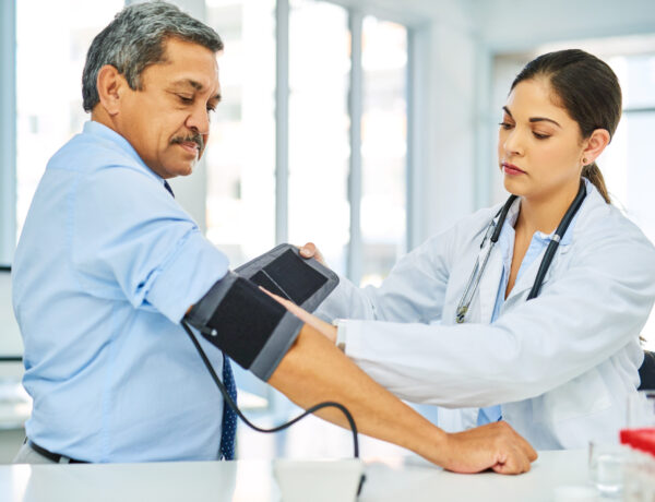 Doctor, man and patient with test, blood pressure and consultation with healthcare, office and checkup. Female person, senior male and medical professional with equipment, hypertension and wellness.