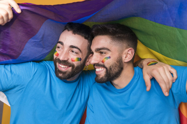 LGBTQ sexual wellness through nutrition - homosexual-couple-men-hugging-lgbt-flag-scaled